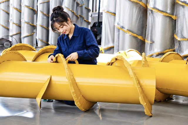 Technician checking yellow fabricated auger components.